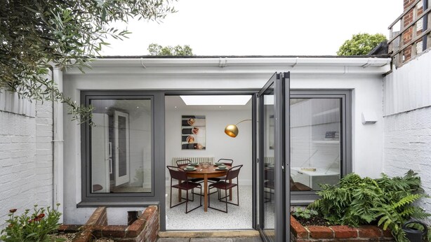 Ein modernes Haus mit Essbereich, Glastür und kleinem Garten.