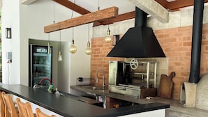 Uma cozinha com uma ilha grande, luminárias pendentes e uma lareira a lenha.