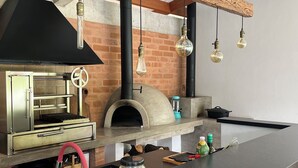 Uma cozinha com forno a lenha, eletrodoméstico de aço inoxidável e luminárias pendentes.
