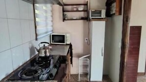 A compact kitchen with a stove, microwave, and a small refrigerator. - La Querencia de Algarrobo: Bungalow No. 4 (Algarrobo)