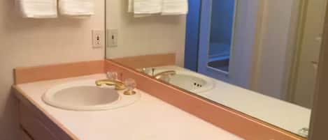 A bathroom with two sinks, a large mirror, and a door leading to another room.