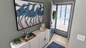 A hallway with a white console table, a blue abstract painting, and a blue and white rug. - Beautiful 3-bedroom Condo with a view for days in Lake Ozark, MO (Lake Ozark)
