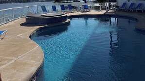 A swimming pool with lounge chairs and a view of the water. - Beautiful 3-bedroom Condo with a view for days in Lake Ozark, MO (Lake Ozark)