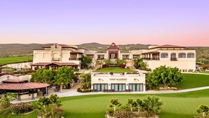 A golf academy with multiple buildings, a well-maintained lawn, and a mountainous backdrop. - Luxury Villa | Large Pool, Jacuzzi & Putting Green (Cabo San Lucas)