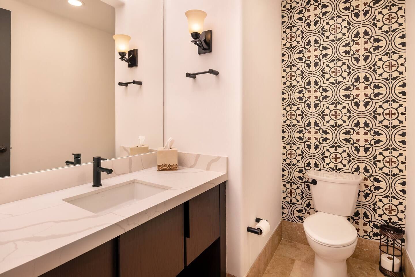 Un baño con lavamanos doble, inodoro y papel tapiz estampado.