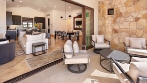 A spacious living area with a dining table, sofas, and a stone accent wall. - Luxury Villa | Large Pool, Jacuzzi & Putting Green (Cabo San Lucas)