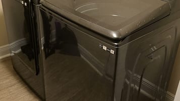 Una unidad de lavadora y secadora de carga frontal, de color negro, con un panel de control en la parte superior.