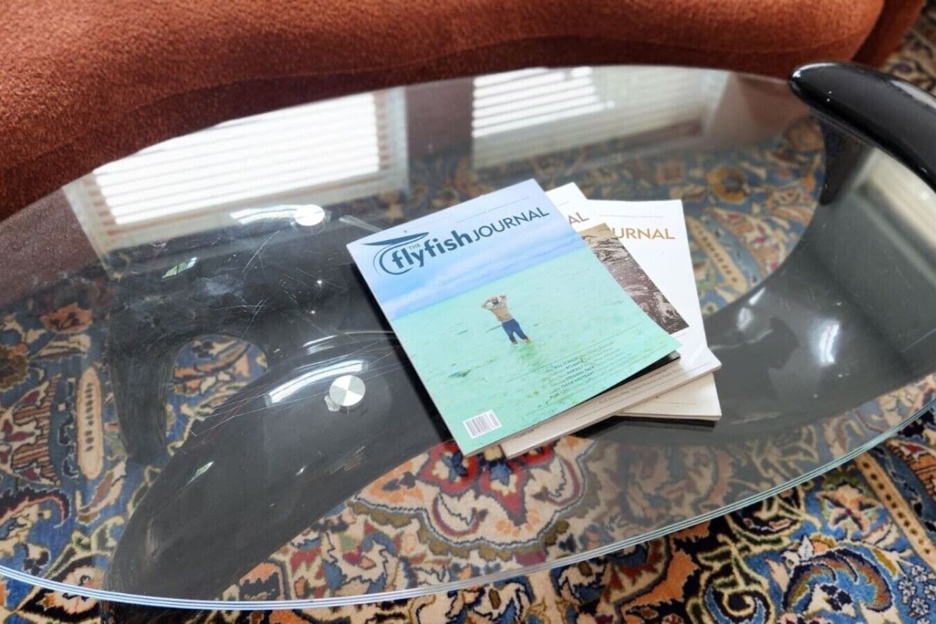 A glass table with a flyfishing journal and a book on it.