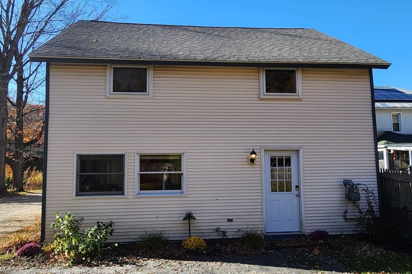 A two-story house with a front door, two windows on the first floor, and a small porch area.