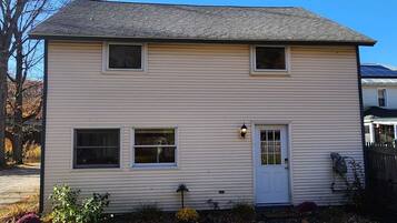 A two-story house with a front door, two windows on the first floor, and a small porch area.