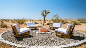 A desert setting with a circular seating area around a fire pit, surrounded by rocks. - Private 5-Acre Joshua Tree Desert Escape - Hot Tub, Fire Pit & Mountain Views (Landers)