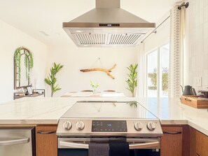 Eine moderne Küche mit einer Edelstahl-Dunstesse, einem eingebauten Backofen und einem großen Fenster für natürliches Licht.