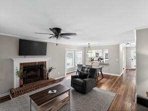 A spacious living room with a fireplace, a dining area, and a kitchen in the background. - Smyrna Townhome: 2 Queens, Patio, 13 Min to The Battery (Smyrna)
