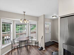 A dining area with a table and chairs, large windows, a door, and a refrigerator. - Smyrna Townhome: 2 Queens, Patio, 13 Min to The Battery (Smyrna)