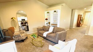 Ein Wohnzimmer mit Sofa, Sessel, Couchtisch und einem dekorativen Schrank.