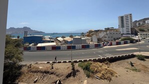 A coastal urban area with buildings, a road, and a clear view of the sea.
