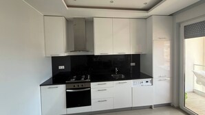 A modern kitchen with white cabinets, black countertops, a stainless steel range, and a dishwasher.