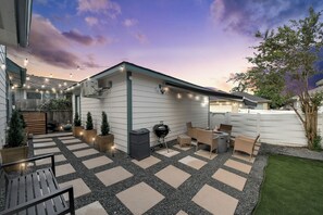 A patio with outdoor furniture, a barbecue grill, and string lights. - Boutique Stay | Prvt Lounge, Arcade, Firepit | 15m IAH (Houston)