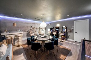 A modern room with a round table, chairs, hanging chairs, and arcade games. - Boutique Stay | Prvt Lounge, Arcade, Firepit | 15m IAH (Houston)