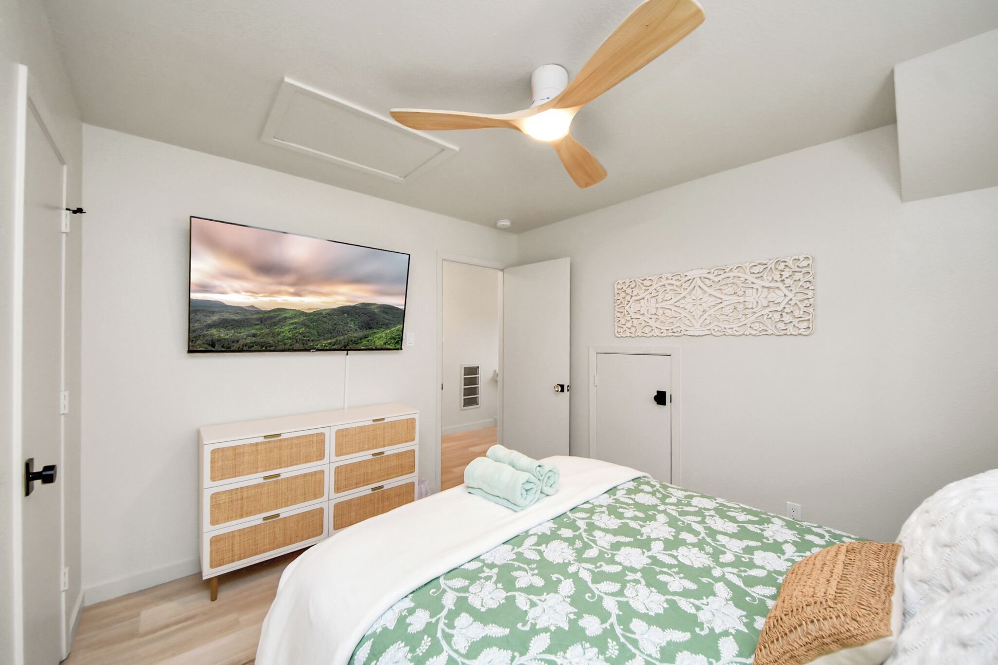 Ein Schlafzimmer mit Bett, Deckenventilator, Fernseher, Kleiderschrank und Wanddeko.