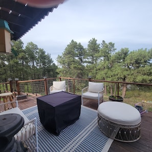 A deck with outdoor furniture, including chairs and a table, overlooking a forested area. - Turkey Ridge Retreat 2 bedrooms w/SPECTACULAR Views (Rapid City)