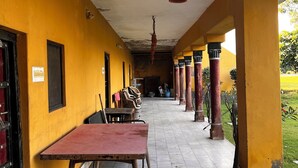 A corridor with a table and chairs, yellow walls, and columns.