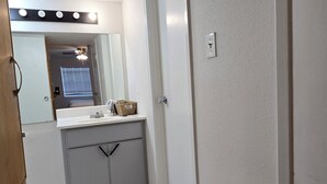 Une salle de bain avec un miroir, un meuble-lavabo et un luminaire au plafond.