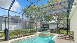 Ein Schwimmbecken mit Glasumrandung, umgeben von einer Terrassenfläche mit Stühlen.