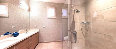 A modern bathroom with a glass shower enclosure, a large mirror, and a wooden vanity with two blue vases.