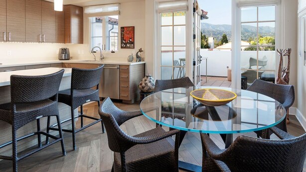 Une cuisine moderne avec des chaises en osier foncé, une table en verre et un ventilateur de plafond.