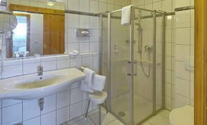 Un baño con ducha de vidrio, lavabo, espejo y retrete.