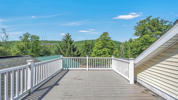 A wooden deck with white railings, surrounded by greenery and trees. - Wonderful 3 bedroom house (Scott)