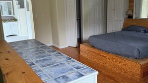 A bedroom with a bed, a wooden bench, a white dresser, and a closet with a mirror. - Wonderful 3 bedroom house (Scott)