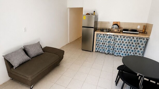 Une cuisine moderne équipée d’un réfrigérateur, d’une cuisinière et d’un cr édence décorée. On y trouve également un canapé et une table à manger avec des chaises.