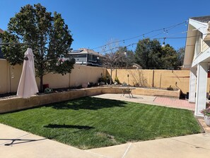 A backyard with a green lawn, a patio table, and a pergola with a white canopy. - ABQ Getaway Kings, 3 Bdrm, 2.5 Bath, Patio Large Yard, Primary Suite & Game Loft (Albuquerque)