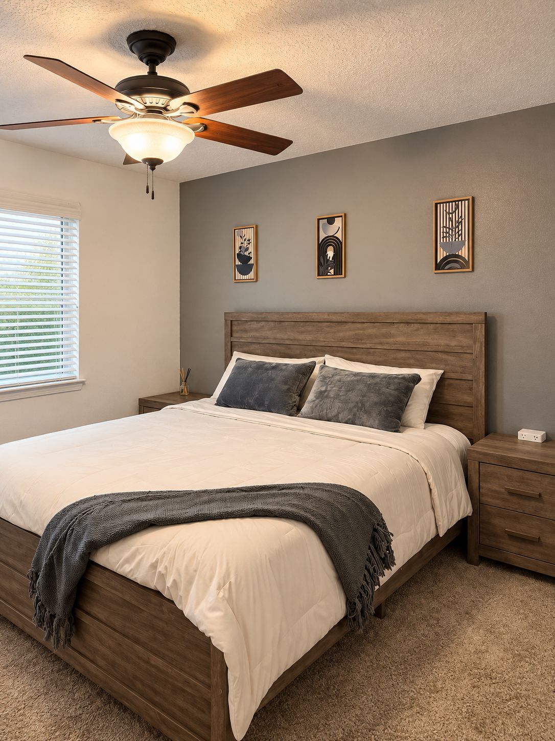 Een slaapkamer met een houten bed, een plafondventilator en drie kunstwerken aan de muur.