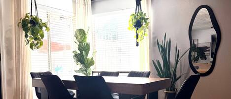 A dining area with a wooden table, black chairs, and hanging plants.