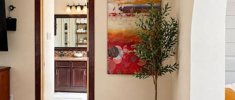 A modern interior with a wooden floor, a large abstract painting, and a potted plant.