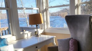 Et værelse med skrivebord, stol og store vinduer med udsigt over vandet.