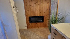 Et badeværelse med trævæg, et fladskærms-tv, en beige måtte og en hvid bænk.