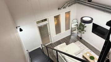 Un interior con una escalera, un sofá, un espejo y una planta en maceta.