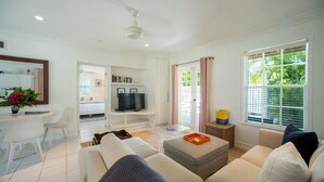 Una sala de estar moderna con un sofá, televisor y un comedor con sillas y una mesa.
