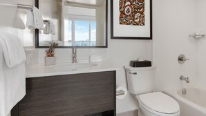 Un baño moderno con lavamanos blanco, tocador de madera oscura, inodoro y bañera.