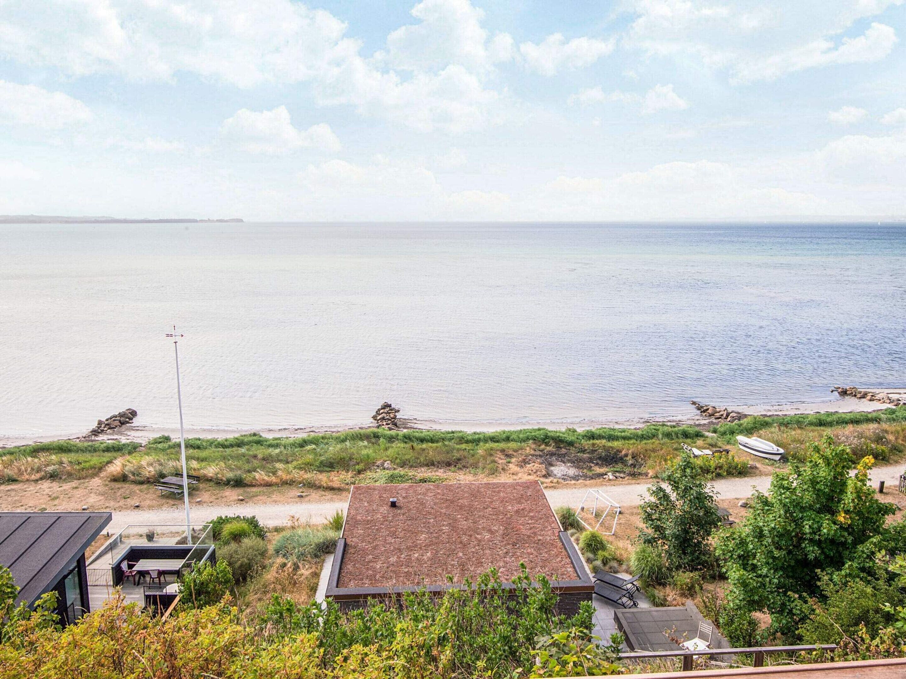 Una propiedad costera con vista al mar, un bote pequeño y una mesa de picnic.