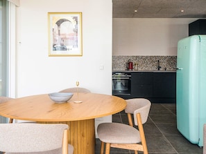 Uma cozinha moderna com uma geladeira azul-turquesa, uma mesa de jantar de madeira com quatro cadeiras e um revestimento de azulejos.
