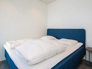 A single bed with a blue headboard in a room with plain white walls. - 5 Star Holiday Home in Ega (Aarhus)