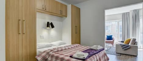 Quarto com cama, guarda-roupa, abajur e vista para o exterior.