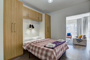 A bedroom with a bed, a wardrobe, a bedside lamp, and a view of the outside. - The Downtown Zando (Montréal)