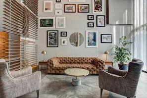 A modern living room with a tufted sofa, a round coffee table, and framed artwork on the walls. - The Downtown Zando (Montréal)