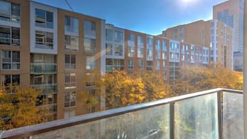 Un edificio a più piani con un balcone in vetro, circondato da alberi autunnali.